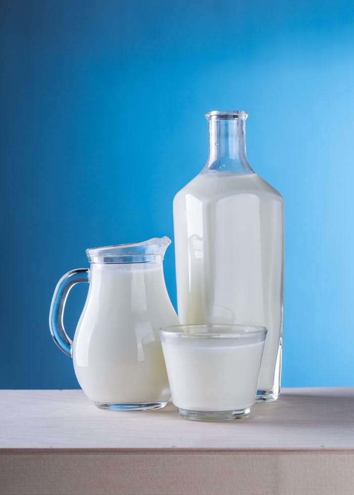 Minimalist still life of fresh milk in glassware against a blue background.